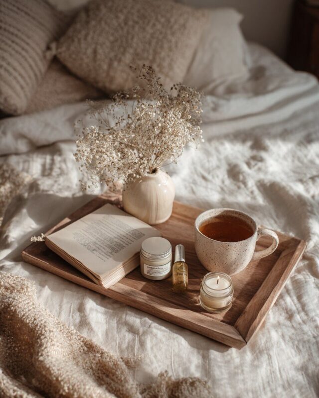 Image d’ambiance bien-être femme avec lumière douce, tasse, produits soin et atmosphère apaisante.
