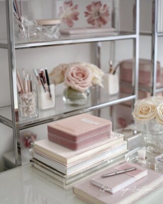 Carnets et boîte rose sur bureau miroir avec stylos organisés et fleurs