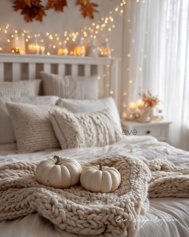 Chambre automne cocooning avec plaid en grosse maille, citrouilles blanches et guirlandes lumineuses.