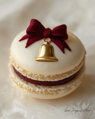 Macaron de Noël doré avec ganache rouge et nœud en sucre sur une table festive