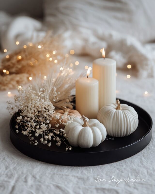 Plateau déco automne minimaliste avec bougies blanches, citrouilles crème et fleurs séchées sur plateau noir.